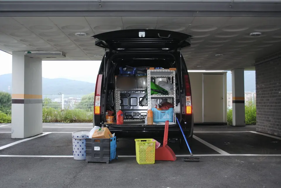 Kapalı otopark girişinde bagajı açık, ekipmanları düzenli servis aracı