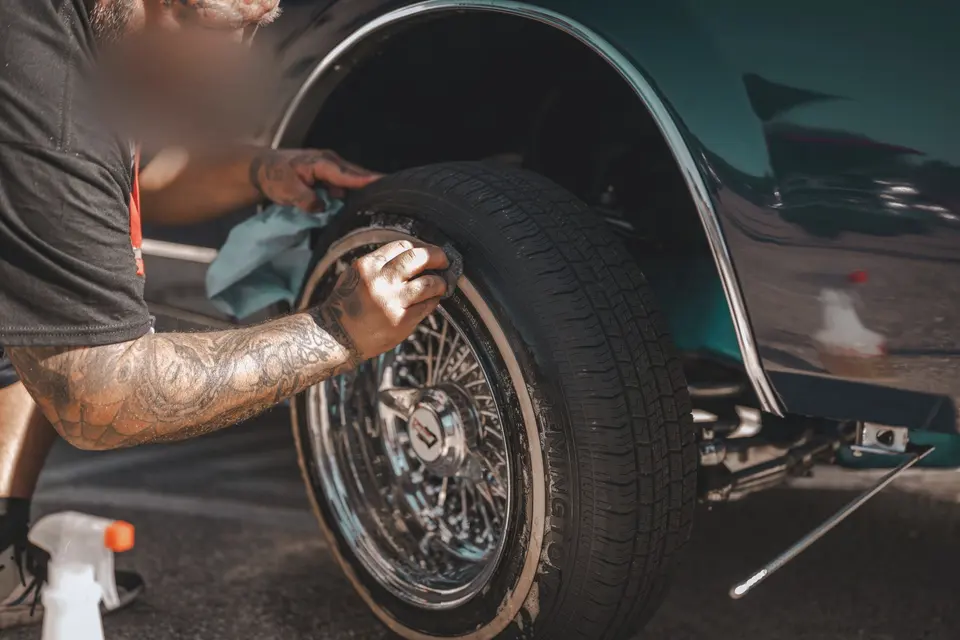 Man Detailing Car Wheel with Cleaning Products