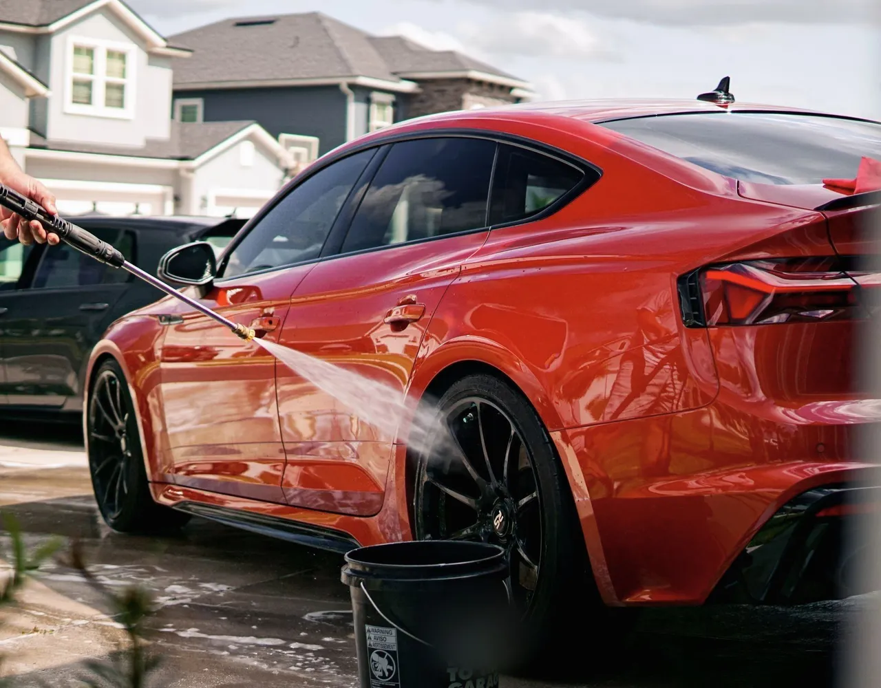 Red Car Being Washed in a Residential District